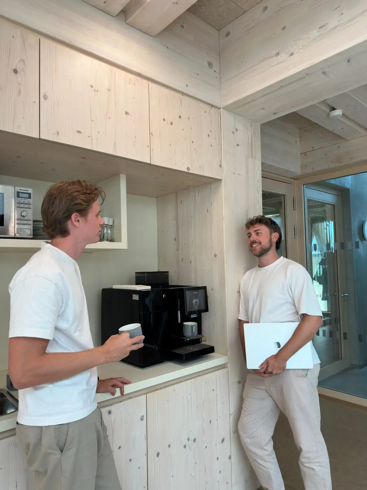 Zwei Teammitglieder von P&A Development im Gespräch an der Kaffeemaschine