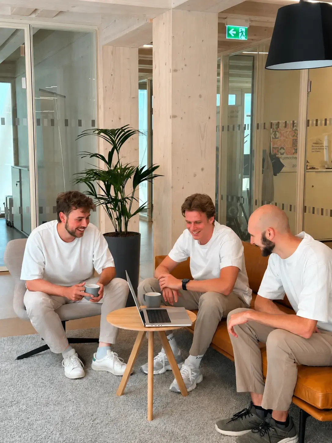 Drei Entwickler von PANDADEV besprechen ein Projekt entspannt auf dem Sofa